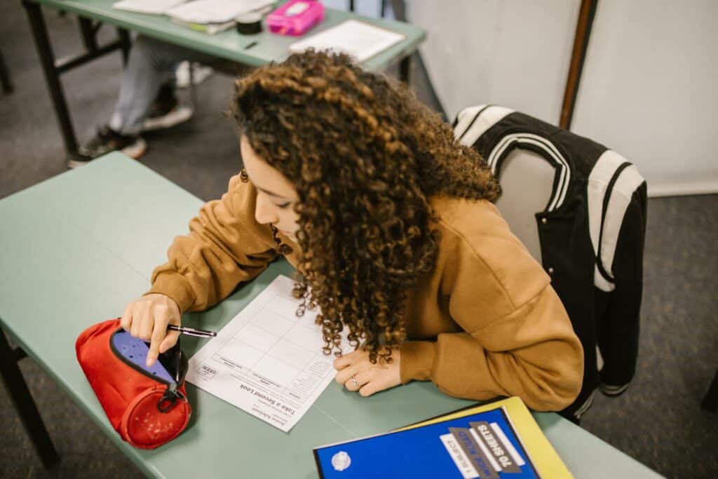 A college student studying for an exam with a smartphone hidden in a pencil case.